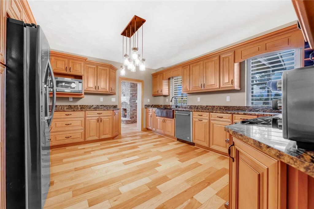 263 Goodwin Road Smithfield, PA 15478 - Photo 29 of 50 a kitchen with stainless steel appliances granite countertop a stove top oven a sink dishwasher and a refrigerator with wooden floor