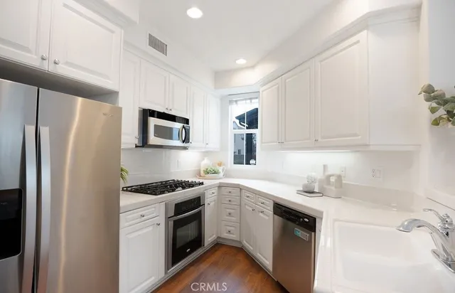 a kitchen with white cabinets sink and stainless steel appliances