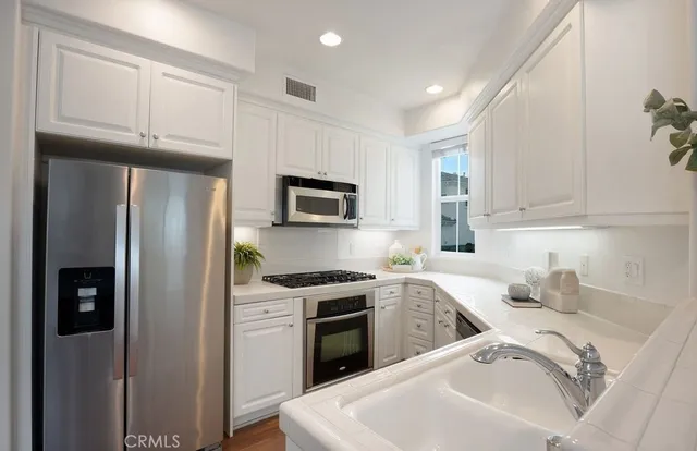 a kitchen with a sink white cabinets and stainless steel appliances