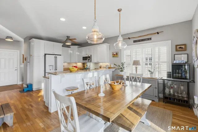 a dining room with stainless steel appliances kitchen island granite countertop a table chairs and a refrigerator
