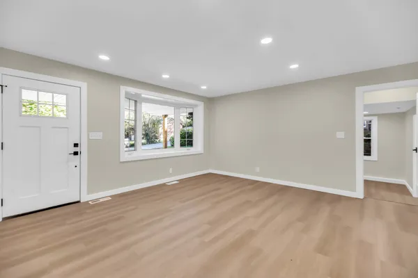 an empty room with wooden floor and windows