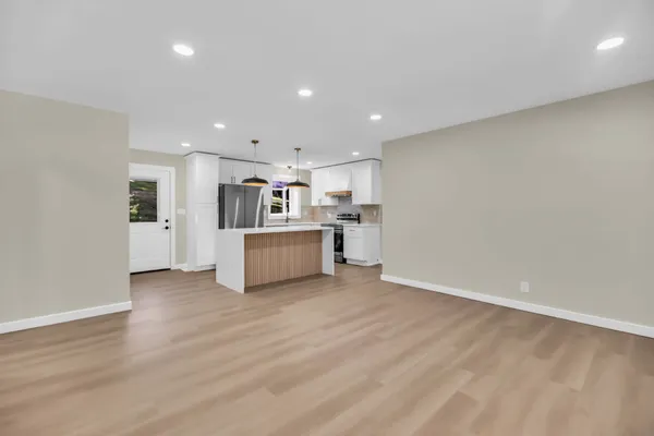 a kitchen with stainless steel appliances a dining table chairs and white cabinets