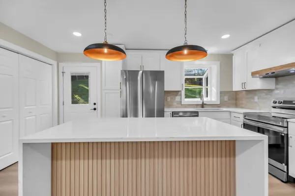 a kitchen with granite countertop a refrigerator and a wooden floor