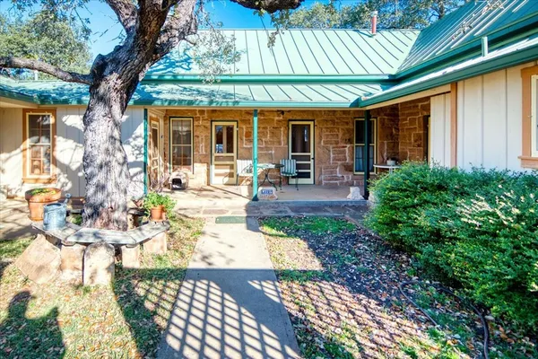 a front view of a house with patio outdoor seating and covered with green space