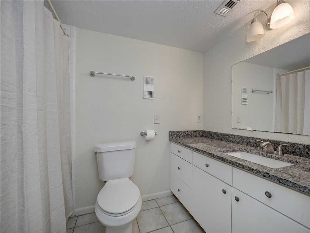 14801 Compass Street, Unit A19 Corpus Christi, TX 78418 - Photo 11 of 18 a bathroom with a granite countertop toilet and a sink