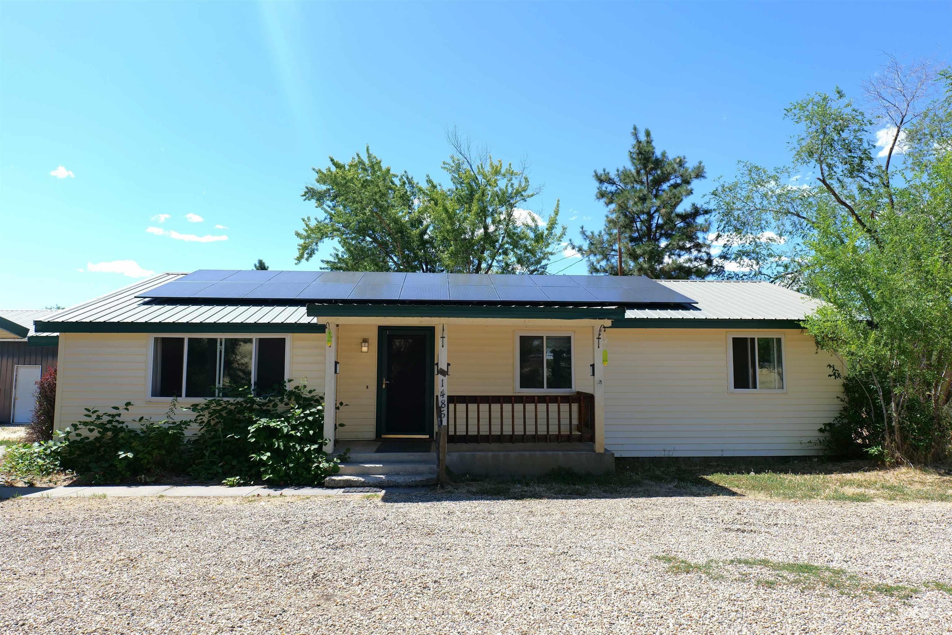 1485 East 9th Street Weiser, ID 83672 - Photo 10 of 18 Single-story residence featuring light-colored siding, solar panels, a metal roof, and a covered front porch with a wood railing