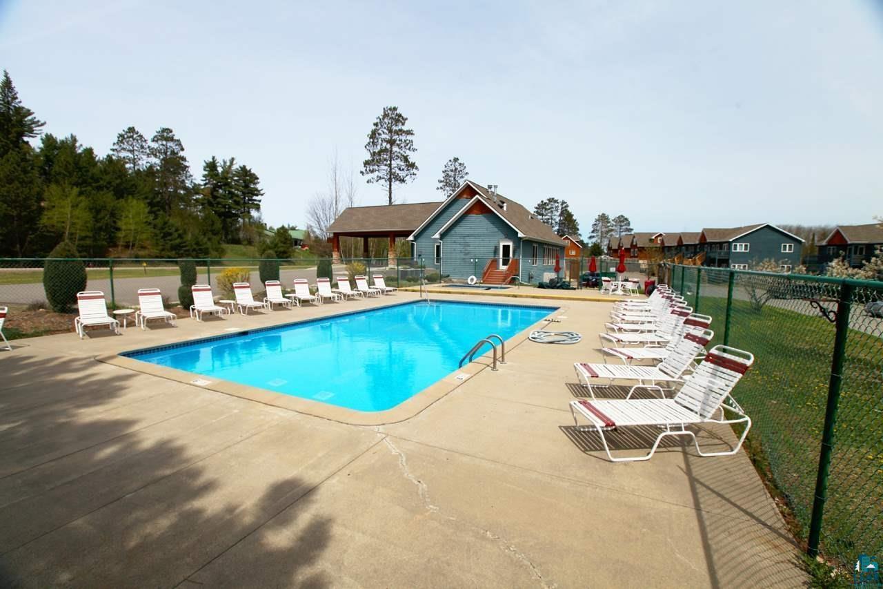6266 Giants Ridge Road, Unit 704 Biwabik, MN 55705 - Photo 22 of 23 Rectangular outdoor swimming pool surrounded by a concrete patio and green chain-link fencing