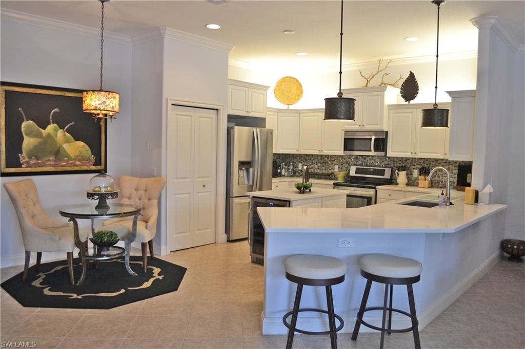 22160 Ponte Romano Lane Estero, FL 33928 - Photo 7 of 17 a kitchen with kitchen island granite countertop a sink a stove and a refrigerator with wooden floor