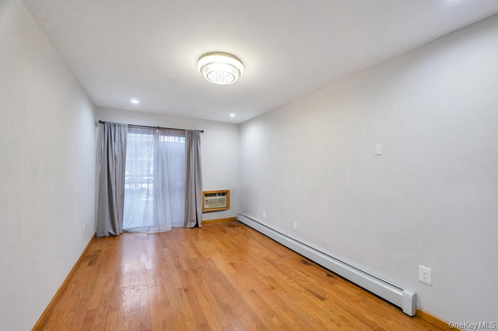 42-11 108th Street, Unit 1A Queens, NY 11368 - Photo 5 of 16 an empty room with wooden floor and sliding door