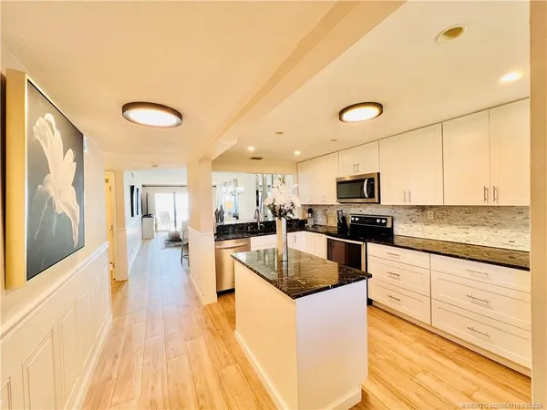 a kitchen with stainless steel appliances granite countertop a refrigerator a stove a sink and a microwave