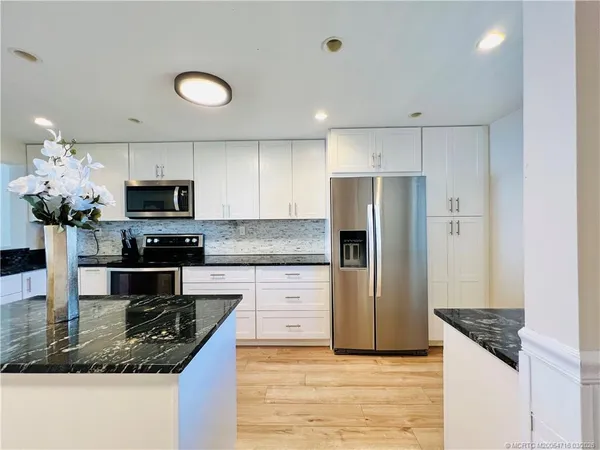a kitchen with granite countertop a sink a stove and cabinets