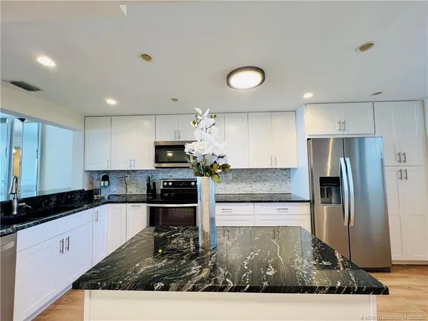 a kitchen with granite countertop wooden cabinets a stove a sink and a refrigerator