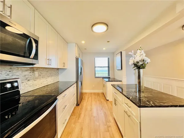 a kitchen with stainless steel appliances granite countertop a stove a sink and a granite counter tops with wooden floors
