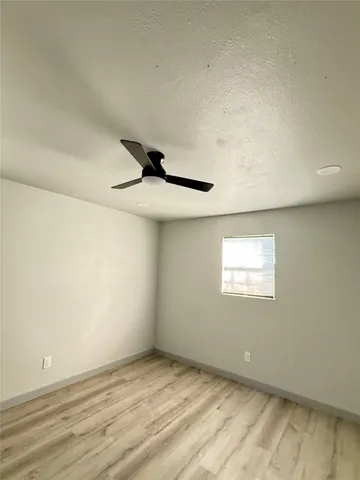 an empty room with a ceiling fan and window