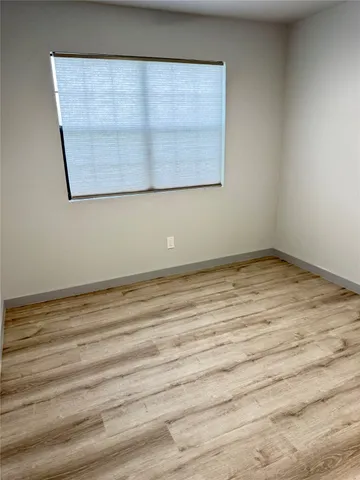 a view of a room with wooden floor and a window