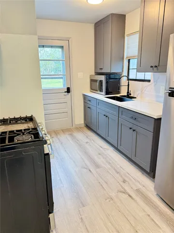 a kitchen with stainless steel appliances a stove a sink and white cabinets