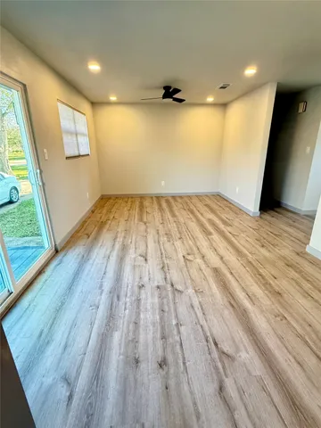 a view of empty room with wooden floor and fan