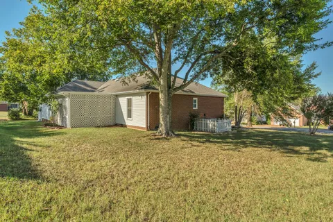 a front view of a house with a garden and tree