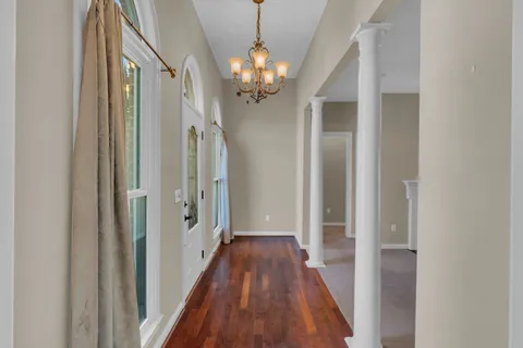 a view of a hallway with wooden floor and chandelier