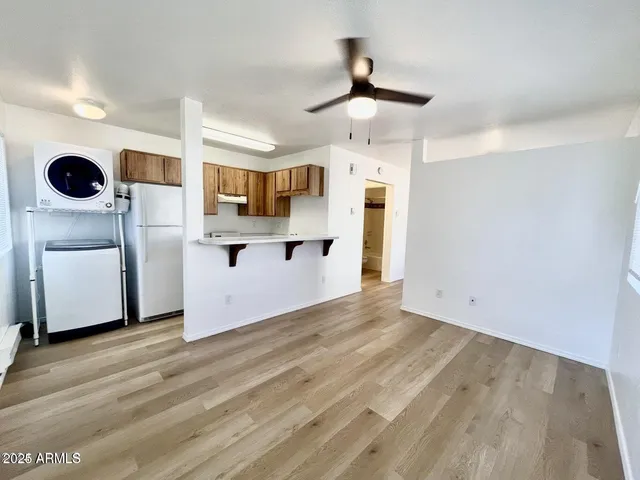 a view of a kitchen with wooden floor a sink a refrigerator and window