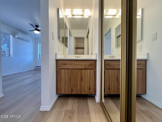 a view of a hallway with wooden floor and a bathroom
