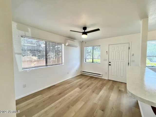 a view of an empty room with a window and wooden floor