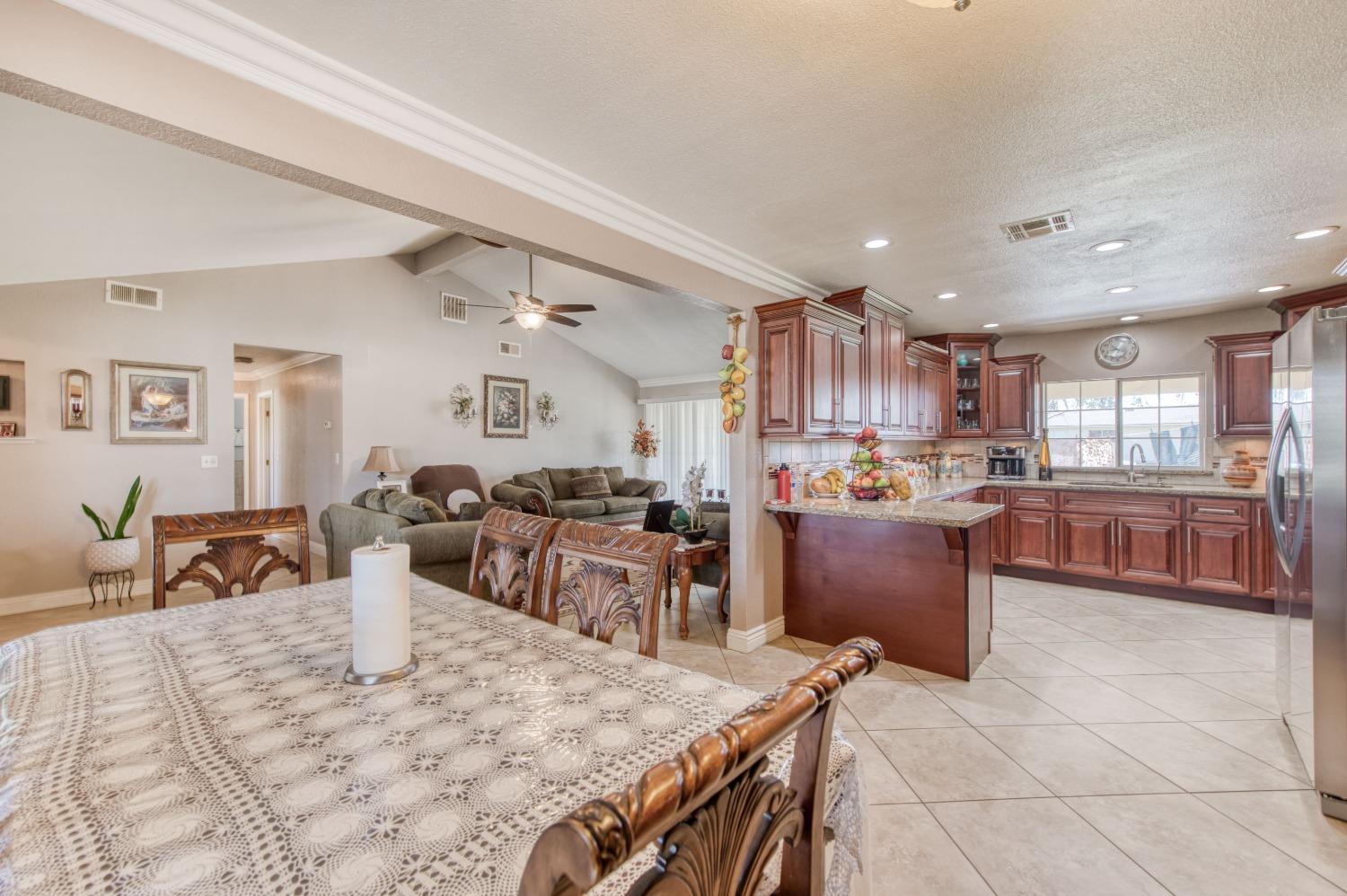25540 Lynn Place, Unit B Madera, CA 93638 - Photo 15 of 37 a kitchen with stainless steel appliances kitchen island granite countertop a refrigerator a stove a sink a dining table and chairs with wooden floor