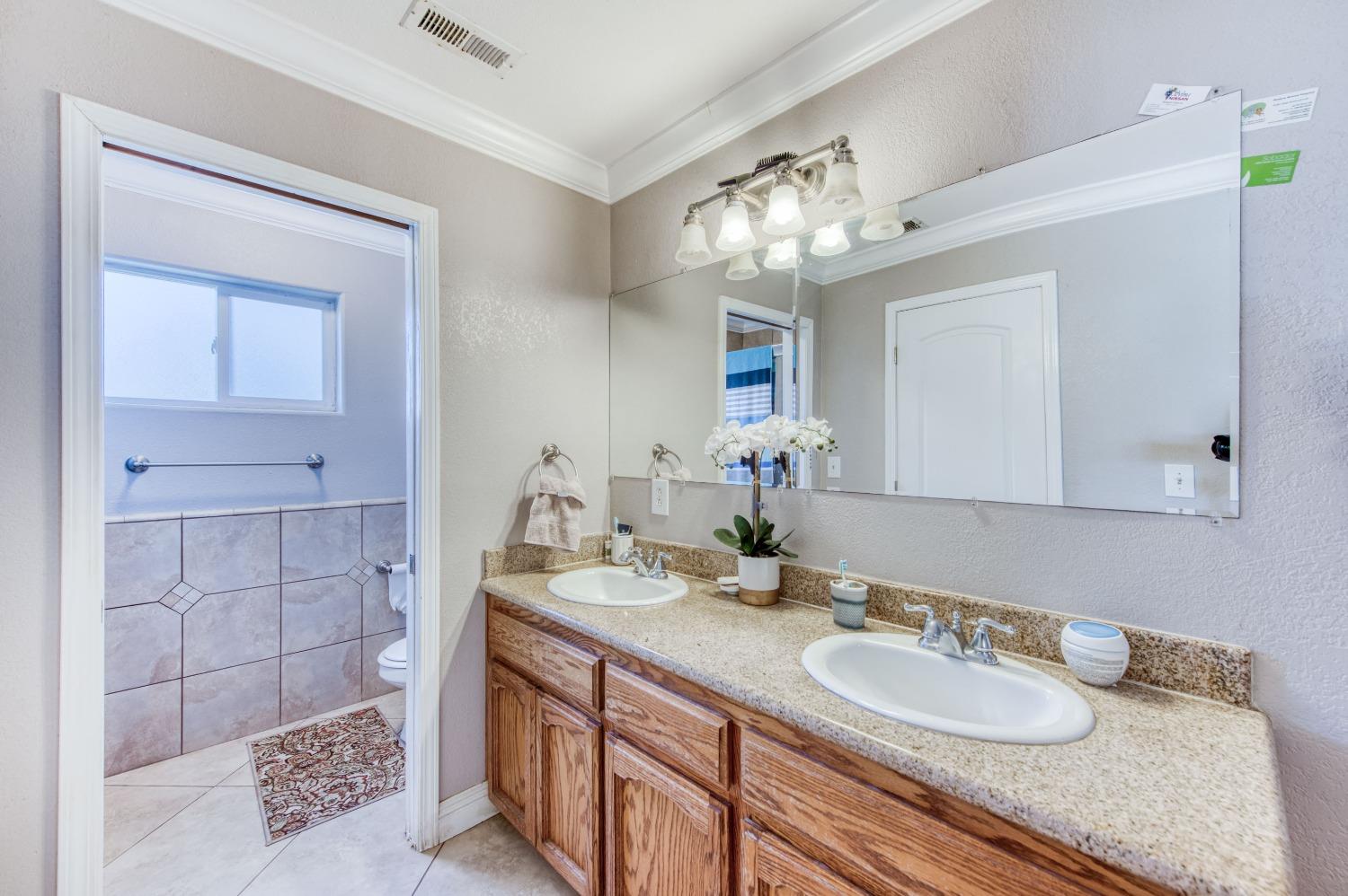 25540 Lynn Place, Unit B Madera, CA 93638 - Photo 20 of 37 a bathroom with a double vanity sink and a mirror