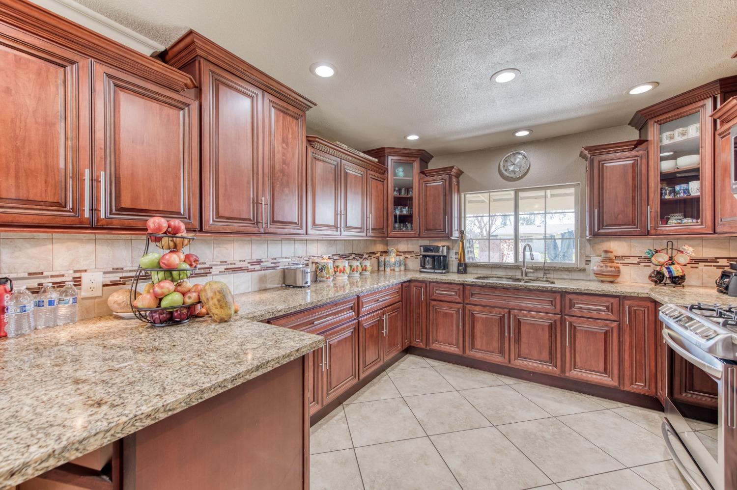 25540 Lynn Place, Unit B Madera, CA 93638 - Photo 3 of 37 a kitchen with stainless steel appliances granite countertop wooden cabinets a sink and dishwasher a stove with wooden floor