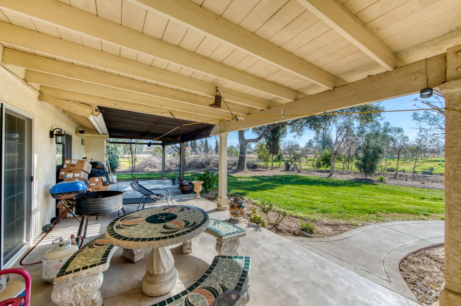 25540 Lynn Place, Unit B Madera, CA 93638 - Photo 34 of 37 a view of a patio with table and chairs potted plants and floor to ceiling window