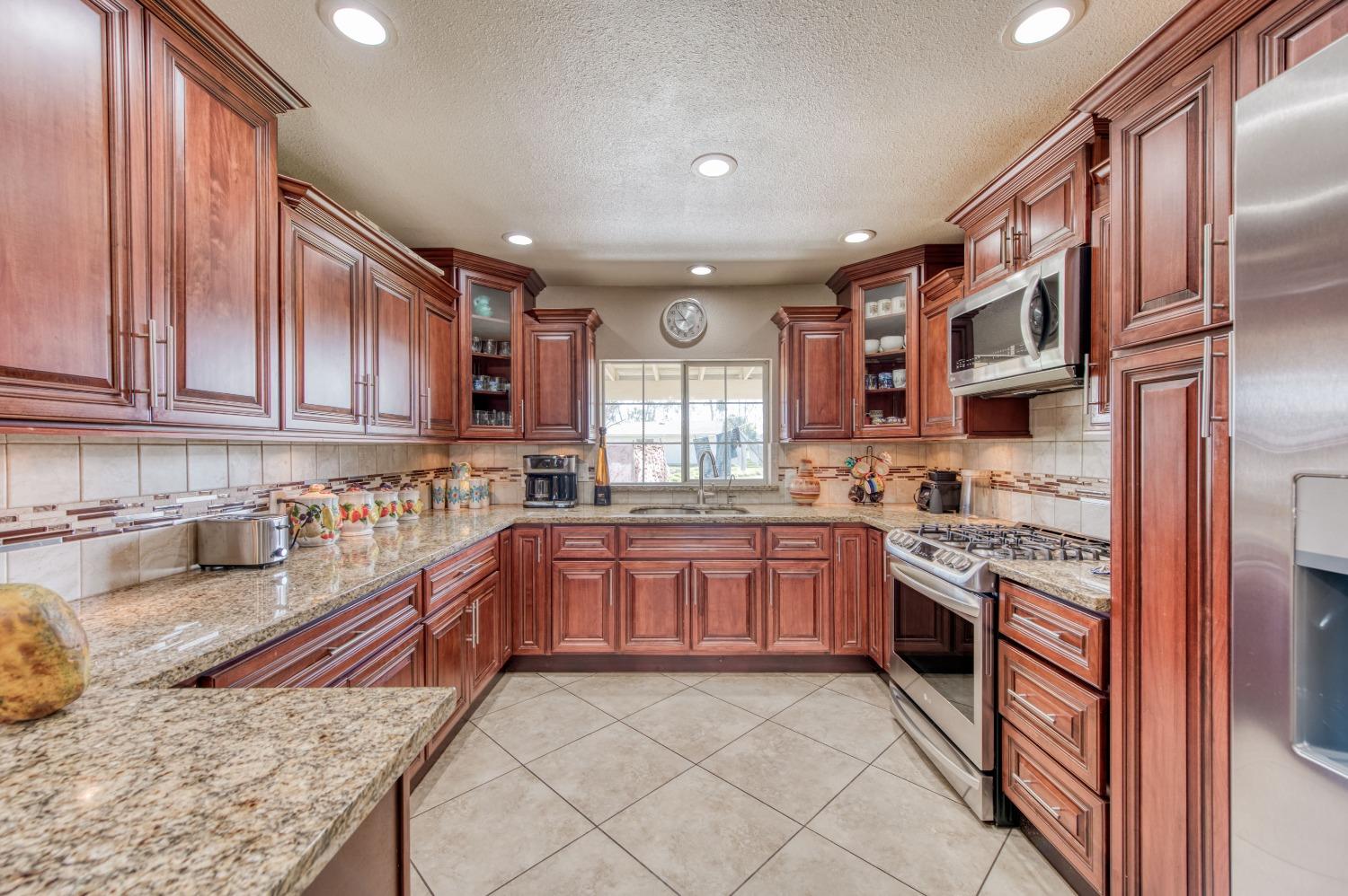 25540 Lynn Place, Unit B Madera, CA 93638 - Photo 4 of 37 a large kitchen with stainless steel appliances granite countertop a stove sink and cabinets