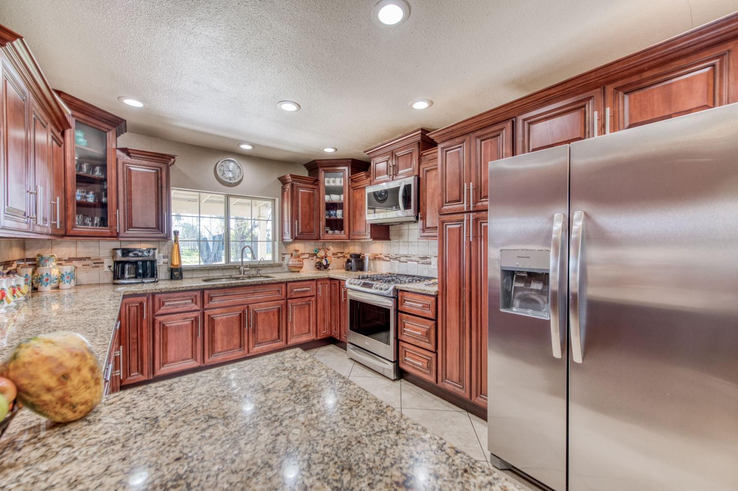 25540 Lynn Place, Unit B Madera, CA 93638 - Photo 5 of 37 a kitchen with stainless steel appliances granite countertop a refrigerator and a stove top oven
