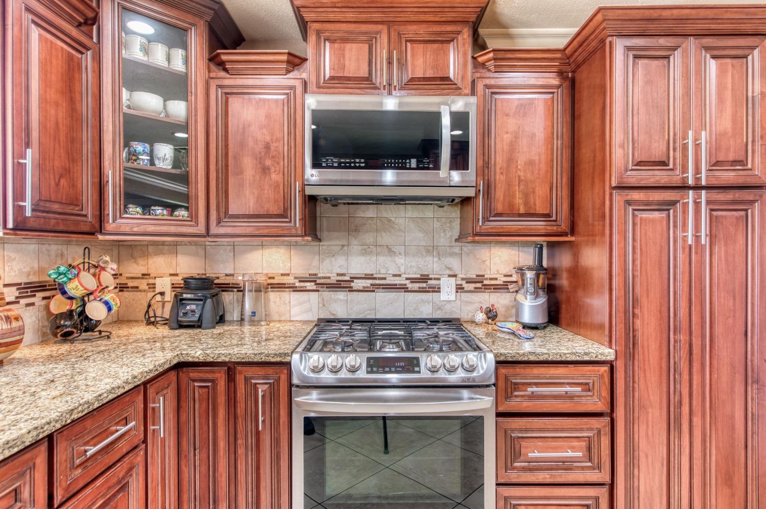 25540 Lynn Place, Unit B Madera, CA 93638 - Photo 8 of 37 a kitchen with granite countertop a stove top oven cabinetry a sink and dishwasher