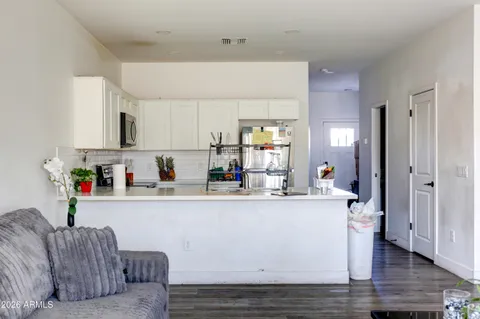 a living room with stainless steel appliances granite countertop a couch and a view of kitchen