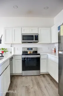a kitchen with granite countertop a stove top oven a sink dishwasher and a microwave oven with white cabinets