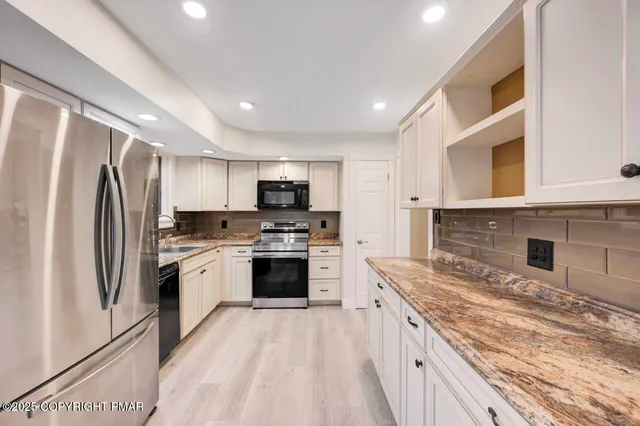 a kitchen with granite countertop a sink cabinets and wooden floor