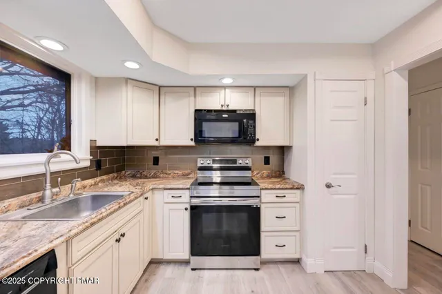 a view of an empty room with wooden floor and a ceiling fan