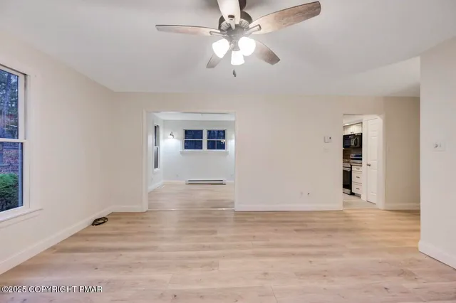 an empty room with ceiling fan and window