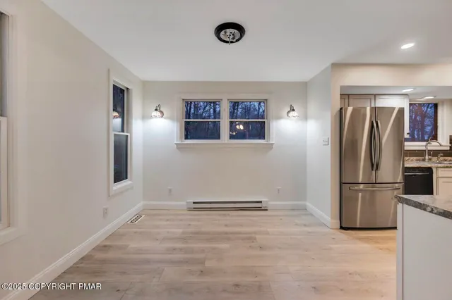 a view of an empty room with wooden floor and a ceiling fan