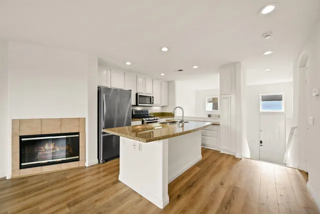 a kitchen with stainless steel appliances granite countertop a stove top oven a sink and a refrigerator