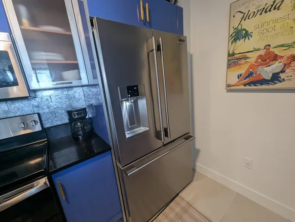 a view of a refrigerator in kitchen and an empty room