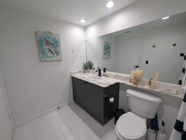 a bathroom with a toilet sink vanity granite and mirror