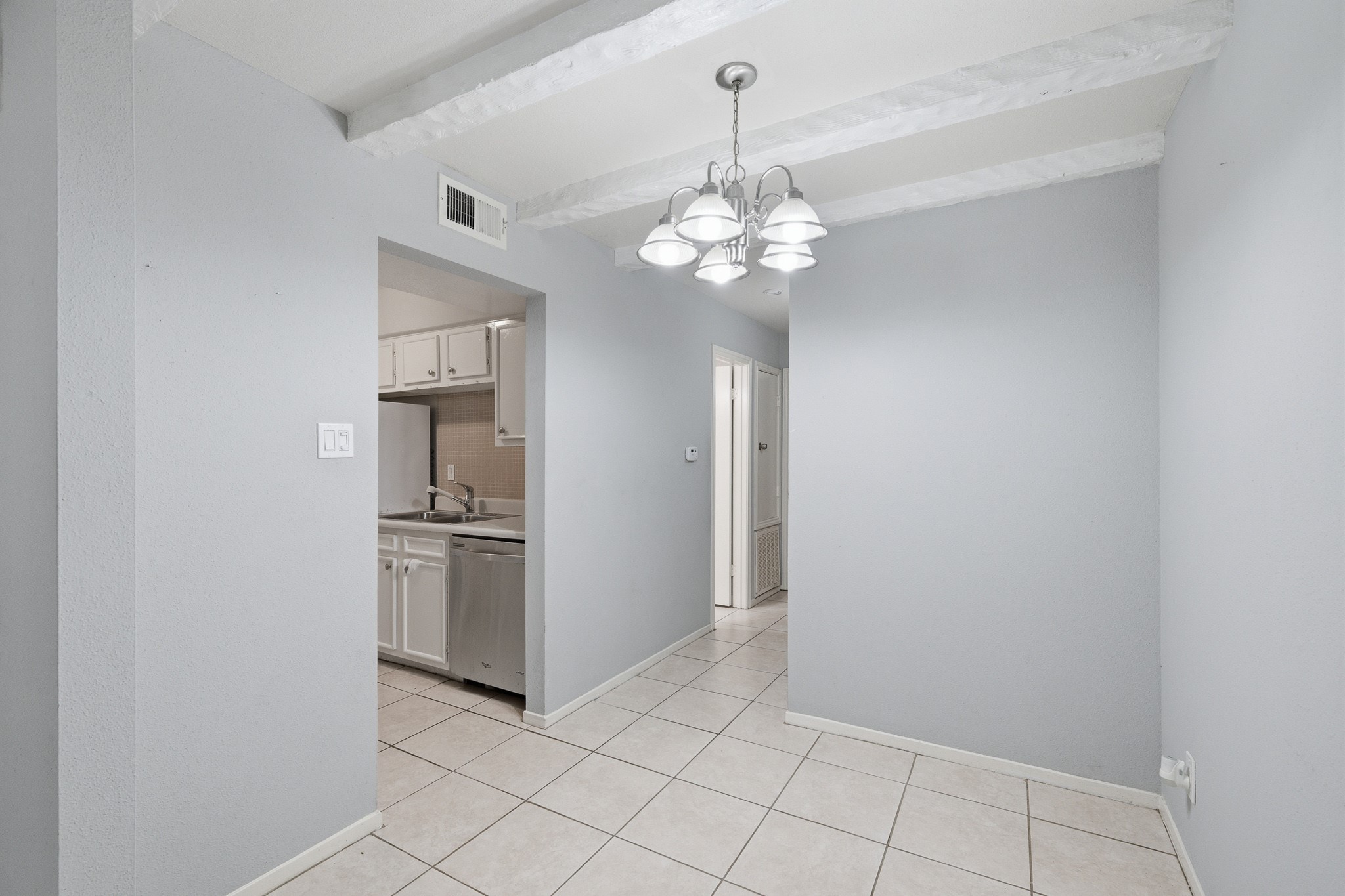 11550 Chimney Rock Road, Unit 133 Houston, TX 77035 - Photo 9 of 40 Dining with tiled flooring, exposed beams, and a cozy chandelier, adjacent to a well-appointed kitchen.