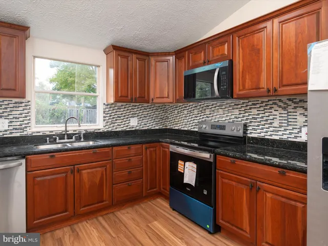 a kitchen with stainless steel appliances granite countertop wooden cabinets a sink and dishwasher
