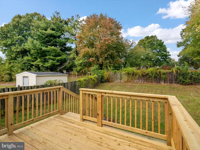 a view of wooden deck and lake with trees in the background