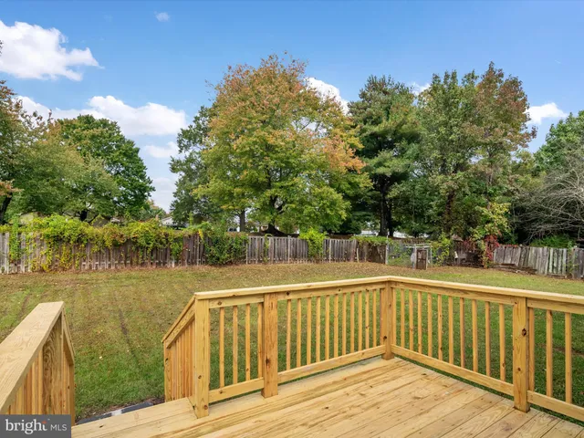 a view of deck and lake with trees in the background