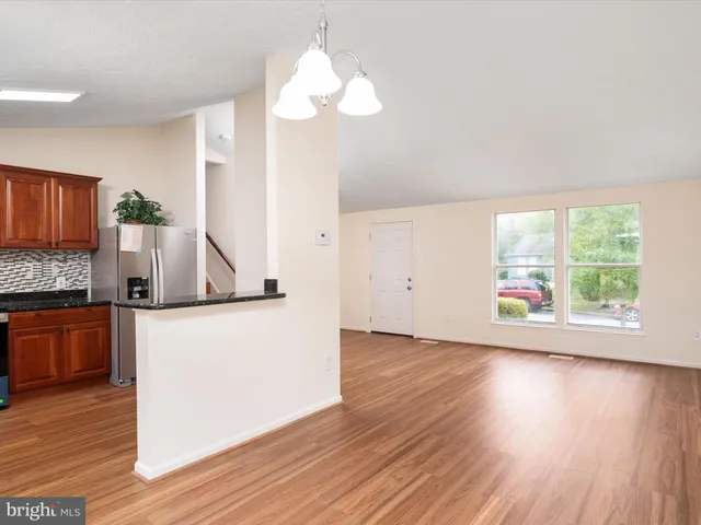 a kitchen with stainless steel appliances granite countertop a stove a sink dishwasher and a refrigerator with wooden floor