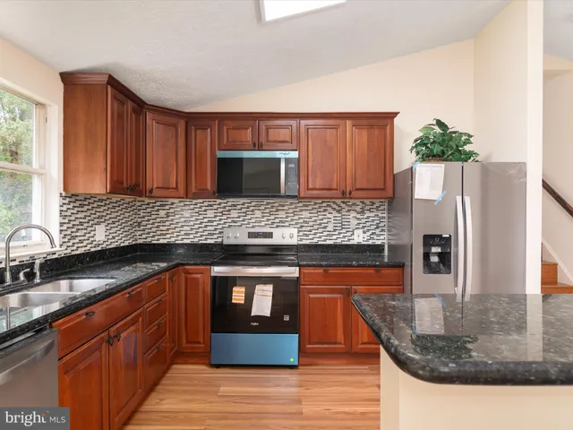 a kitchen with stainless steel appliances granite countertop a sink and a stove