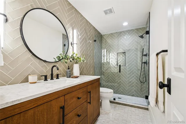 a bathroom with a granite countertop sink a toilet and a mirror