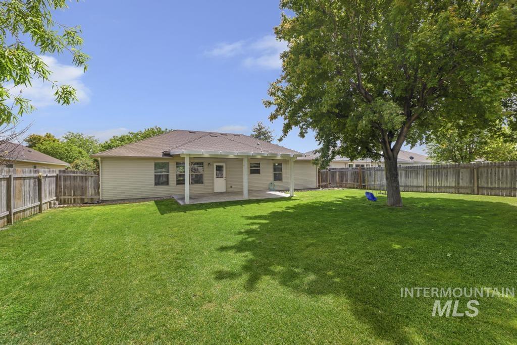 1183 Cortes Loop Twin Falls, ID 83301 - Photo 26 of 30 Expansive green lawn featuring a mature shade tree, a covered back patio, and full perimeter fencing